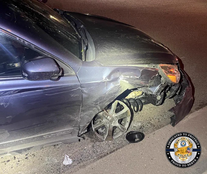 Front right side of a dark car severely damaged with the wheel detached and suspension exposed on a road at night.