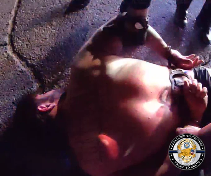 A man lying face down on the ground in handcuffs.