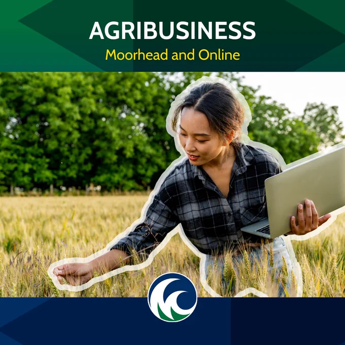 A person holding a laptop examines crops in a field. The image promotes an agribusiness program in Moorhead and online, with a logo resembling waves at the bottom.