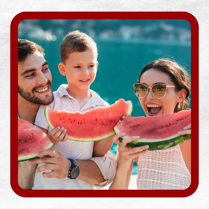 Three people outdoors holding slices of watermelon with a blue body of water in the background.
