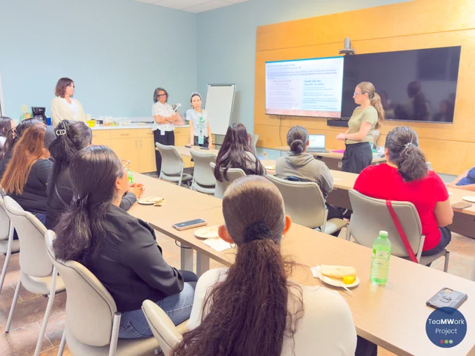 Facilitators lead a discussion at the front of the room with slides on identifying indirect disclosures of violence, as participants seated at tables engage in the workshop and review materials.