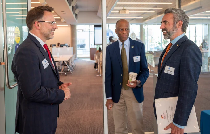 Three men dressed in business attire talk to each other.