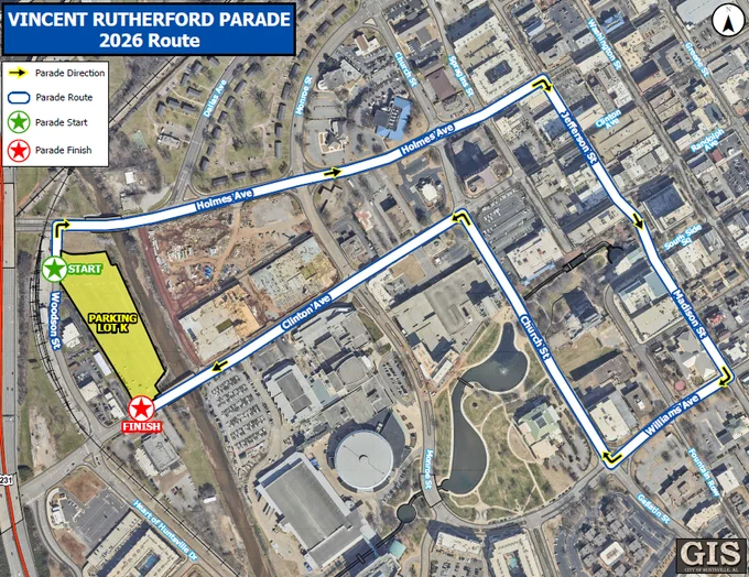 A detailed city map shows the 2026 route for the Vincent Rutherford Parade. A bold blue line marks the parade route, with yellow arrows indicating the direction of travel. The route begins at a green star labeled “Start” on Woodson Street, next to a large highlighted area marked “Parking Lot K.” The route continues along Holmes Avenue, Jefferson Street, Clinton Avenue, Church Street, Williams Avenue, Madison Street, and back toward the starting area. A red star labeled “Finish” is located near the bottom left of the map. Street names, buildings, and surrounding landmarks are visible, and a legend in the top left corner explains the icons for parade direction, route, start, and finish. The title at the top reads “Vincent Rutherford Parade 2026 Route.”