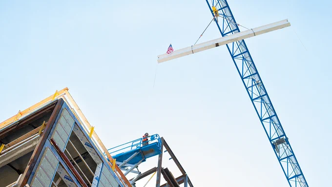 A crane hoists the final beam to the top of Pachyderm Place. Photo: Alonso Nichols/Tufts University