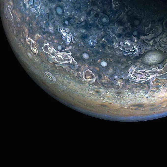Enhanced color image of a portion of Jupiter's cloud surface, revealing swirling storms and large cells, shown in shades of blue, brown, and cream. 