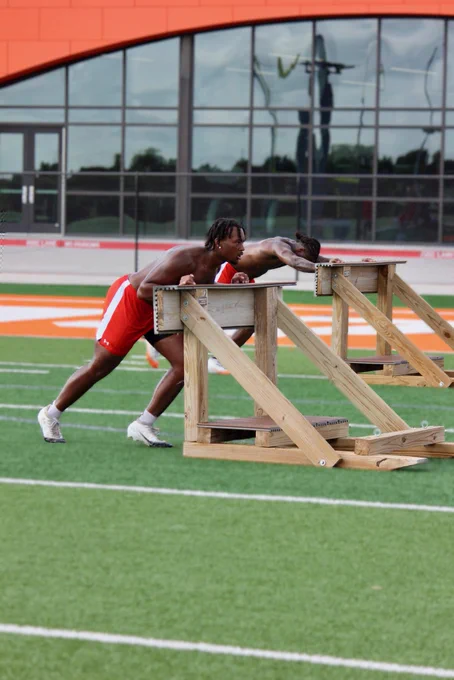 Athletes pushing wooden sled across turf field