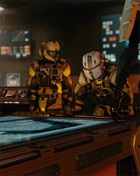 A photo from Starfield featuring two characters in yellow and white space suits standing around a high-tech table. The room has various screens displaying data and lights, and Vasco can be seen at the table as well.