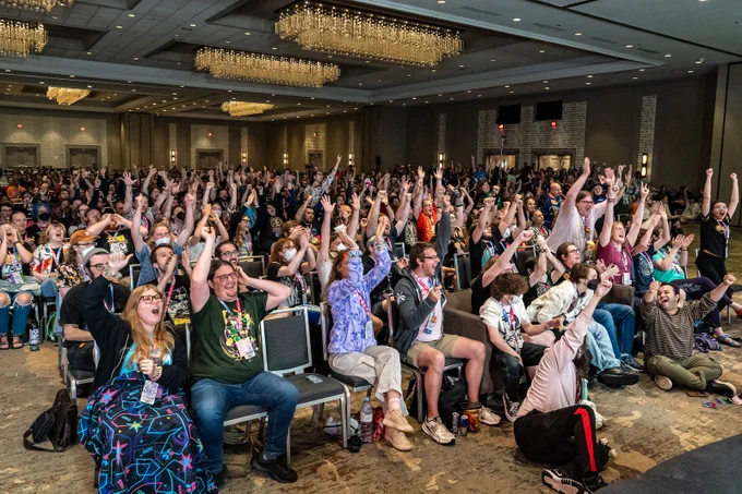 crowd of GDQ attendees raising their arms and cheering in the stream room