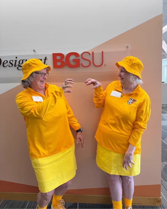 Two bgsu alumni wearing matching outfits at Golden Falcons event