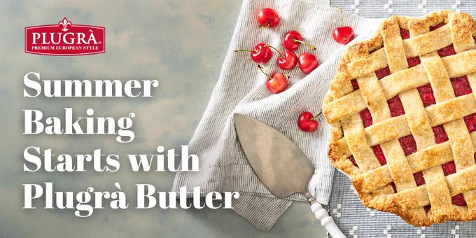 A lattice-topped cherry pie in a white dish sits on a table near additional loose whole cherries. Text reads "Summer Baking Starts with Plugrá Butter." Plugrá logo is visible.