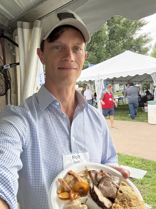 Rob Sand attends the World Pork Expo and takes a selfie holding a plate of food.