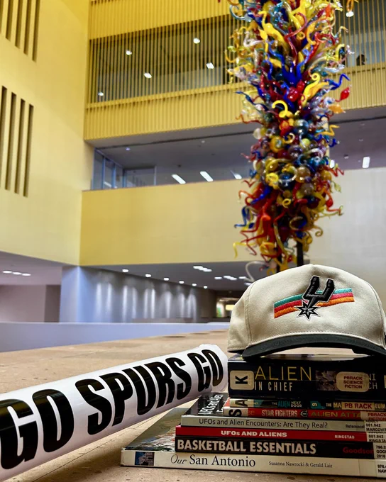 Stack of books with a spurs hat on top of them in a library setting