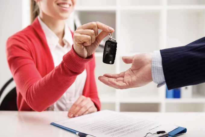 person hand car keys to another person