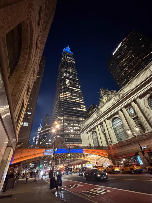 Pershing Square Bridge lit in orange and blue lights at Grand Central Terminal in the evening.