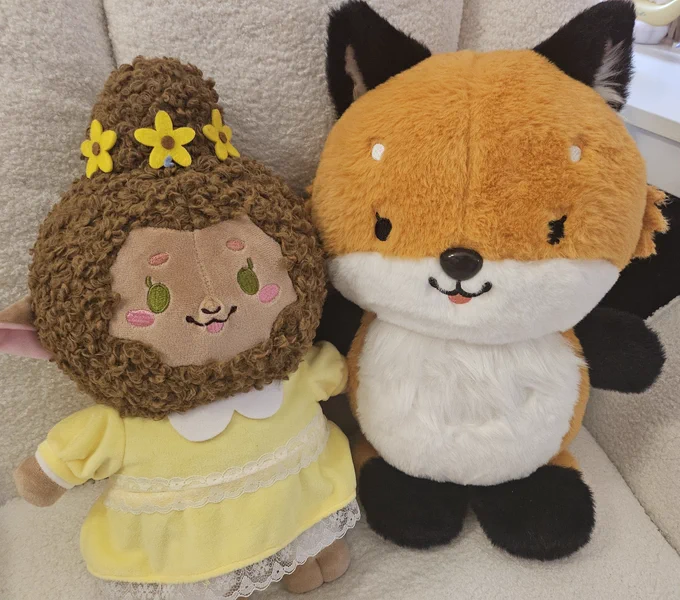 A pair of bipedal stylized plushies. One is a brown sheep, the other an orange fox.