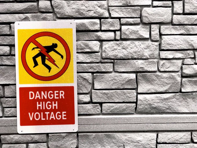 High voltage warning sign on a textured brick wall, Vancouver, BC.