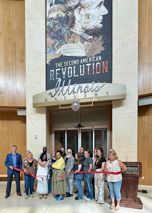 A group cuts a red ribbon to open a museum exhibit called "The Second American Revolution."