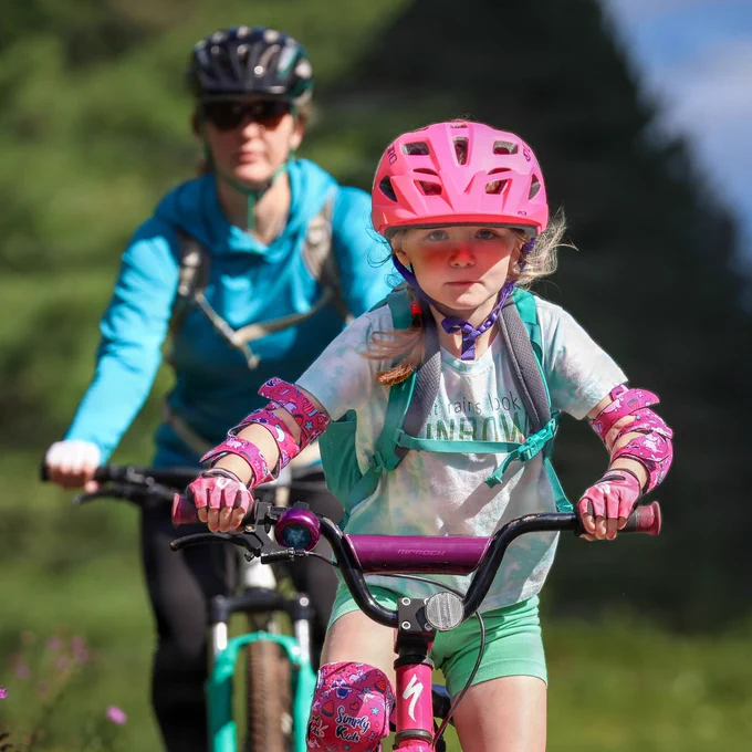 Kid and parent ride bikes.