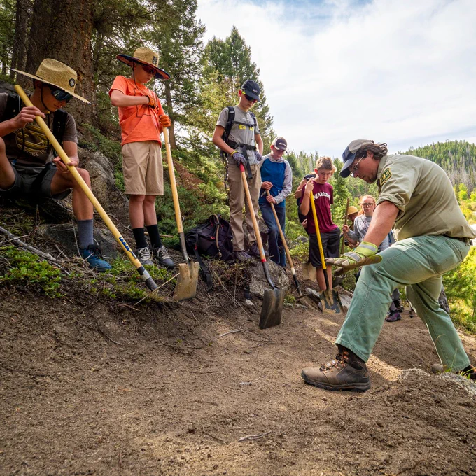 Forest Service employee shows volunteers how to repair a trail.