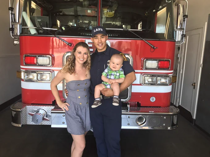 Kelly Wong, his wife and his child standing in front of a fire engine.