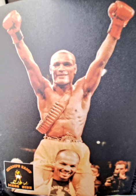 Photo of black boxing champion Frank Grant, fists aloft, on shoulders of smiling trainer Phil Martin
