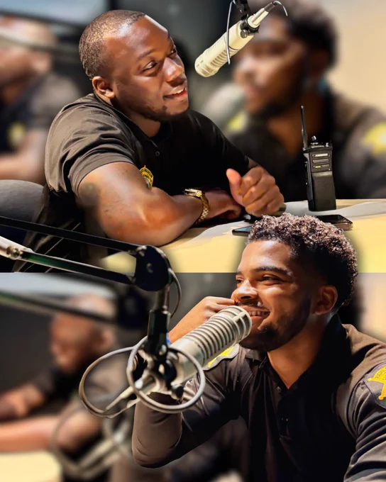 Two deputies are speaking into microphones in a radio studio. One person looks engaged, with a radio set beside them, while the other appears to be smiling. Both are wearing dark shirts, and there's a blurred background showing studio equipment. They shared details of an upcoming flag football game: Richland County Sheriff's Department vs Columbia Police Department. The game is part of the Ju'Stice Games. It's at 4:00pm at WJ Keenan High School.
