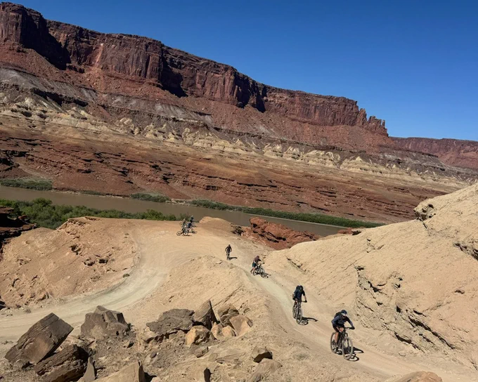 Five adults biking along a canyon trail.
