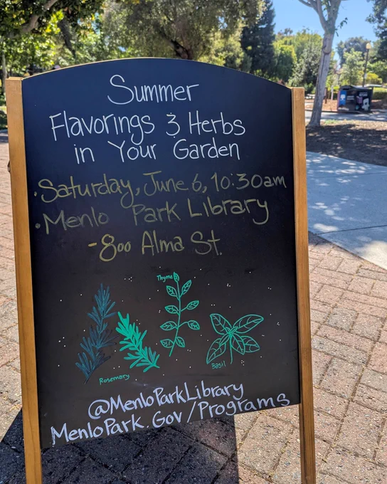 A photo taken in front of the library shows a standing blackboard on the brick walk, with trees and the book drop in the background. On the  blackboard are drawings of herbs including basil and fennel. 
Text: SUMMER FLAVORINGS & HERBS IN YOUR GARDEN - Saturday, June 6, 10:30 a.m.-12:30 p.m. - Menlo Park Library, 800 Alma St.
@Menloparklibrary 
https://www.menlopark.gov/Government/Departments/Library-and-Community-Services/Events/Events-for-children/20260606-Garden-Talk-Herbs-in-person