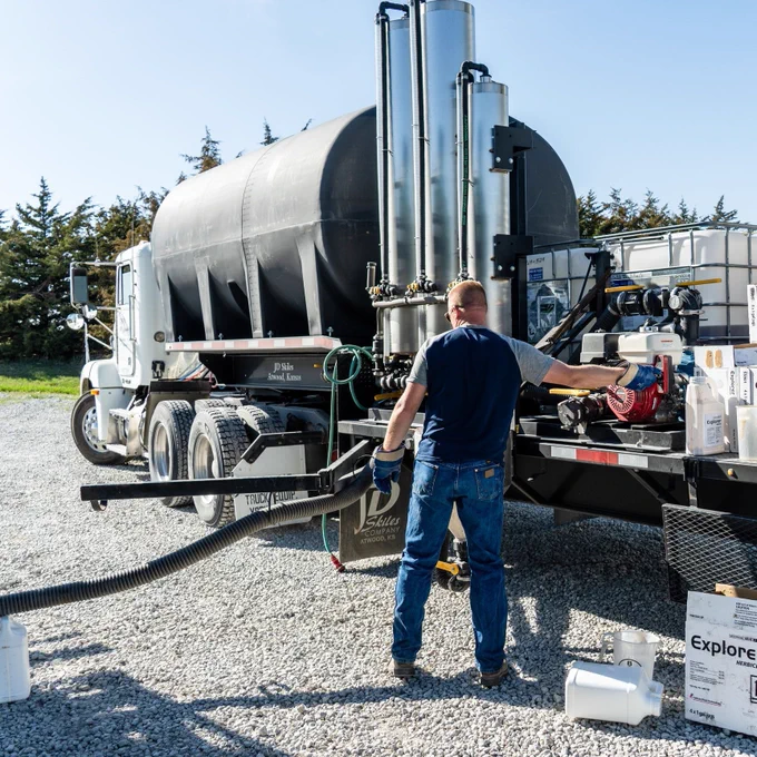 Farmer starting engine to pump liquid from truck into sprayer.