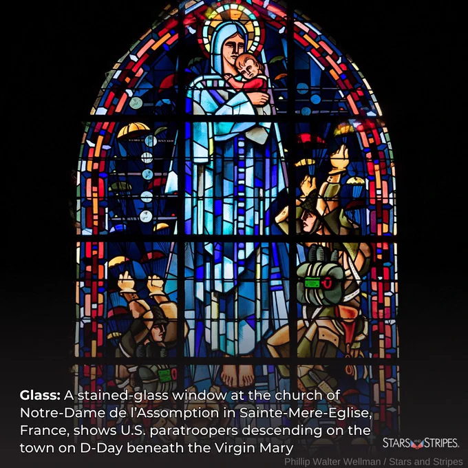 A stained glass window depicts the Virgin Mary, holding an infant Jesus, as U.S. paratroopers fall from the sky. White text: Glass: A stained-glass window at the church of Notre-Dame de l'Assomption in Sainte-Mere-Eglise, France, shows U.S. paratroopers descending on the town on D-Day beneath the Virgin Mary; white Stars and Stripes logo; Photo credit: Phillip Walter Wellman/Stars and Stripes