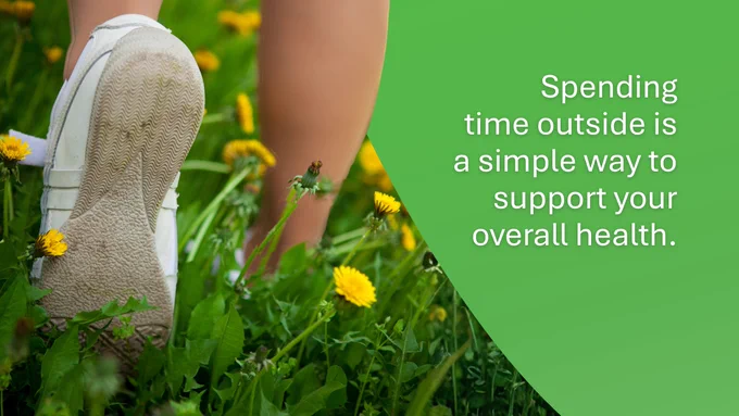 Alt text: 
A bright photo of a person mid-stride walking through green grass and dandelions. The photo is cropped at the calves so only their shoes and bottom of their legs are seen. Text on the image reads: Spending time outside is a simple way to support your overall health.

