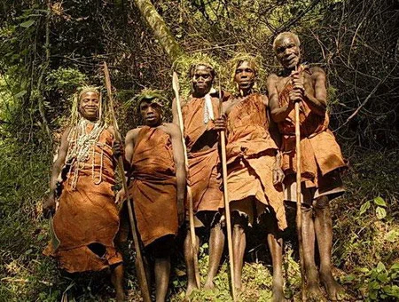 five Batwa people in traditional brown clothes in the forest