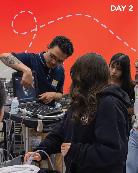 Label “Day 2” on top-right corner with an orange-red background shows a small group of students gathered around a portable ultrasound machine in a classroom setting. An instructor stands beside the machine, pointing to the ultrasound monitor while explaining the imaging, as students watch closely. In the foreground, one student holds an ultrasound probe against a simulation surface, while gel and equipment are visible on the cart. Dashed graphic lines overlay the background as part of the design.