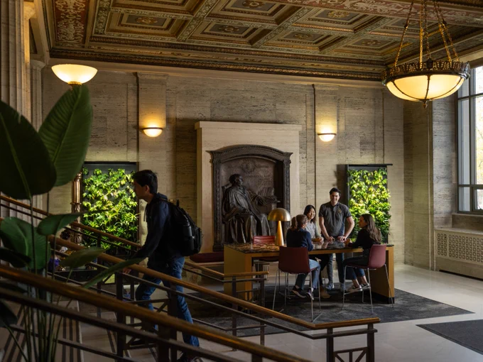 Students stand and chat with one another in LSA's Angell Hall