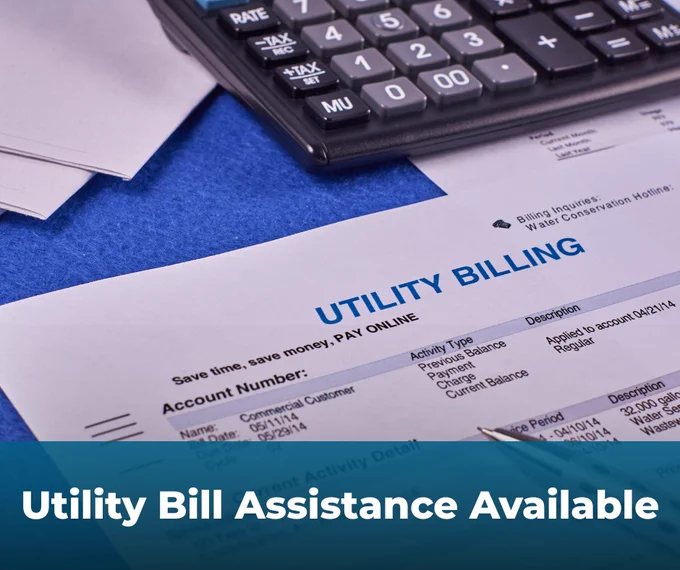 A utility bill next to a calculator on a blue desk. White text over a blue rectangle says utility bill assistance available. 