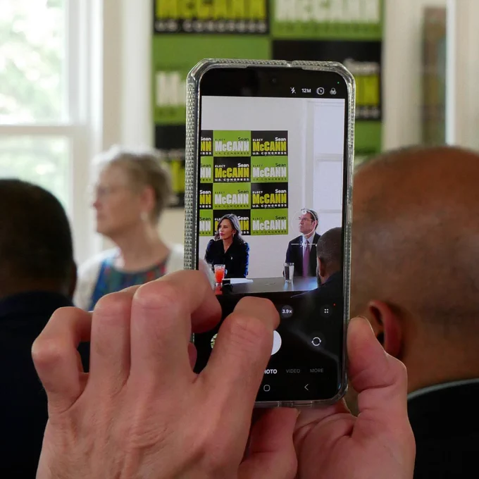 An attendee taking a photo of Governor Whitmer and Sean McCann.