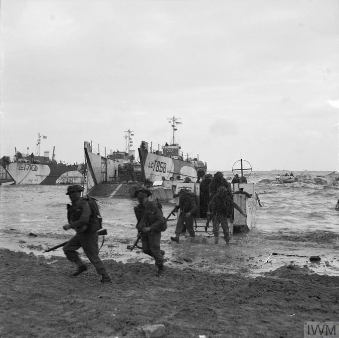 World War II scene depicting troops disembarking from landing crafts onto a beach, with one vessel marked "LCI 758." The environment is overcast, and waves are visible near the shore.