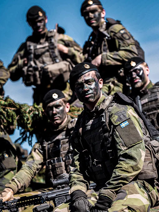 Swedish soldiers in uniform gathered during a training exercise.