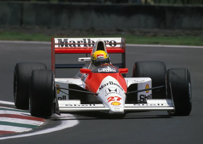 Ayrton Senna steers around the kerbs of a right hand corner in his red and white, Marlboro sponsored McLaren MP4/5B. Similar to its predecessor, it has smaller sidepod vents. 1990 Mexican Grand Prix.