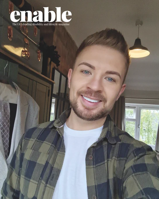 An image of Luke Manton. He is smiling, has short brown hair and a circle beard, and is wearing a dark green and black chequered flannel and a white t-shirt.