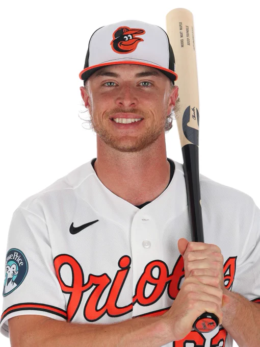 Reed Trimble looks at the camera and smiles while holding a bat over his shoulder. He is wearing a white Orioles jersey and a tri-color cap.
