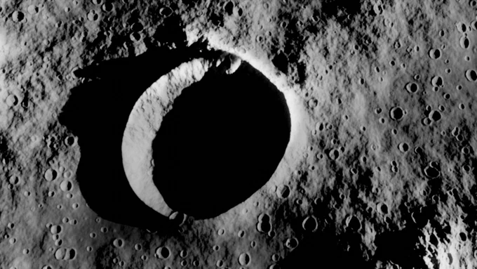 The surface of the Moon. It's covered in craters, with one extremely larger crater amongst them all.