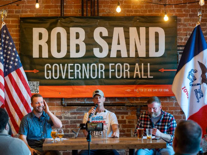 A photo of Rob Sand at an event speaking with the hosts of Pints & Diplomacy. 