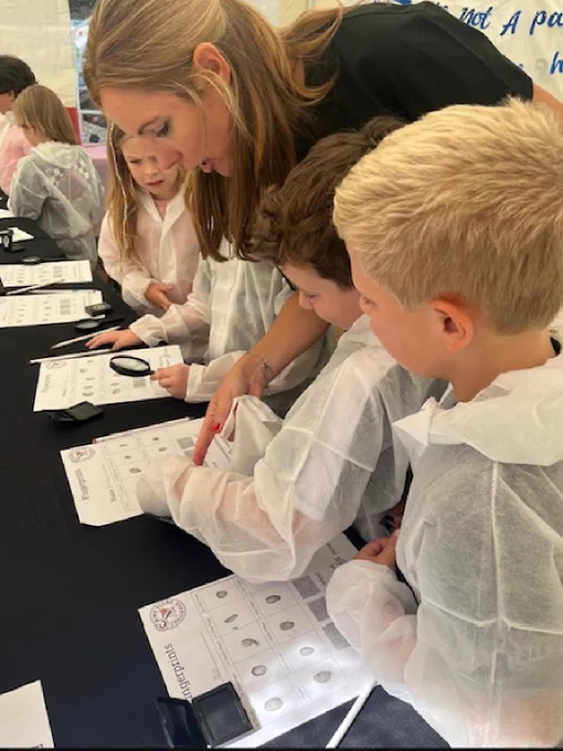 Children being supervised by adult learning how to dust for fingerprints.
