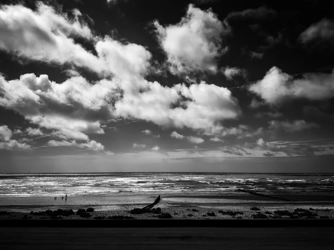 A dramatic, high-contrast black and white photograph of a rough and churning English Channel, taken from a window on the Sussex coast. The sea is filled with whitecapped, choppy waves under a moody, heavily overcast, and stormy sky stretching toward a dark horizon.