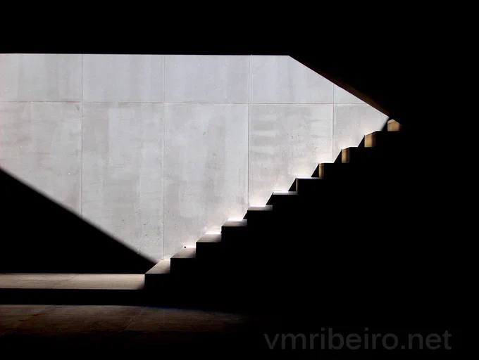 Escada interior com linhas geométricas e luz natural a incidir sobre os degraus.