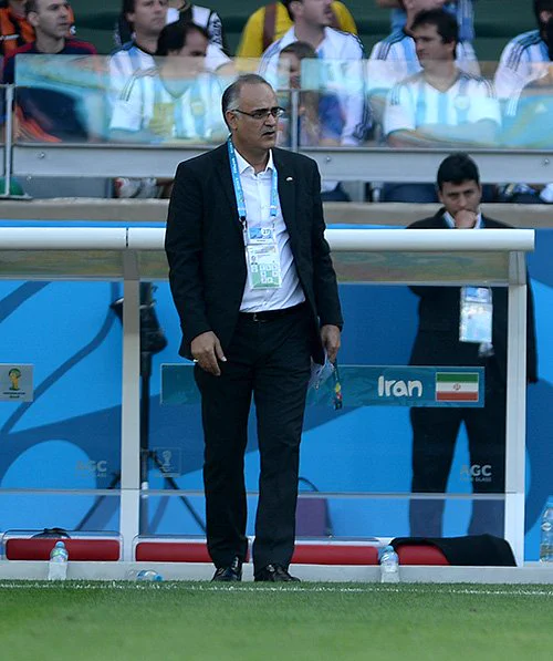 Iranian team manager Mehdi Mohammadnabi pitch side in a suit.