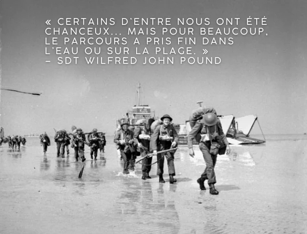 Photo en noir et blanc de soldats munis de lourds sacs à dos marchant sur le replat de marée, des embarcations de débarquement en arrière-plan. Texte sur l’image : « Certains d’entre nous ont été chanceux... mais pour beaucoup, le parcours a pris fin dans l’eau ou sur la plage. » – Sdt Wilfred John Pound