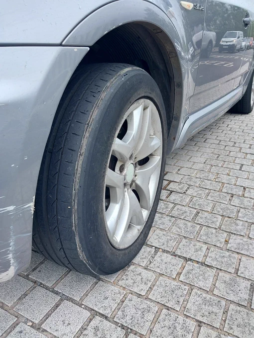 Picture of the front passenger side tyre of a Grey BMW X3. It shows that the chord and metal parts of rhe tyre are exposed all the way round the outer edge of the tyre
