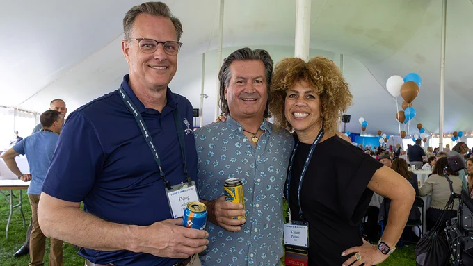 Three alumni posing for a photo while standing under a tent during Tufts Reunions